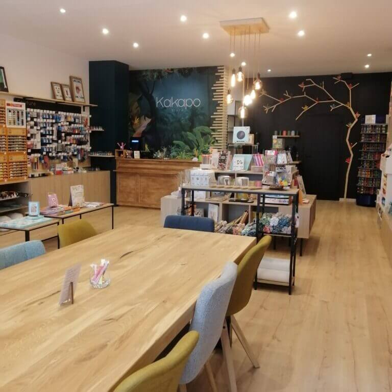 Grande table en bois dans l'espace atelier lumineux de la boutique Kakapo à Marseille, dédiée au crochet et aux loisirs créatifs.